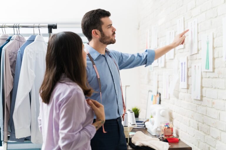 Male tailor pointing to female coworker in textile industry